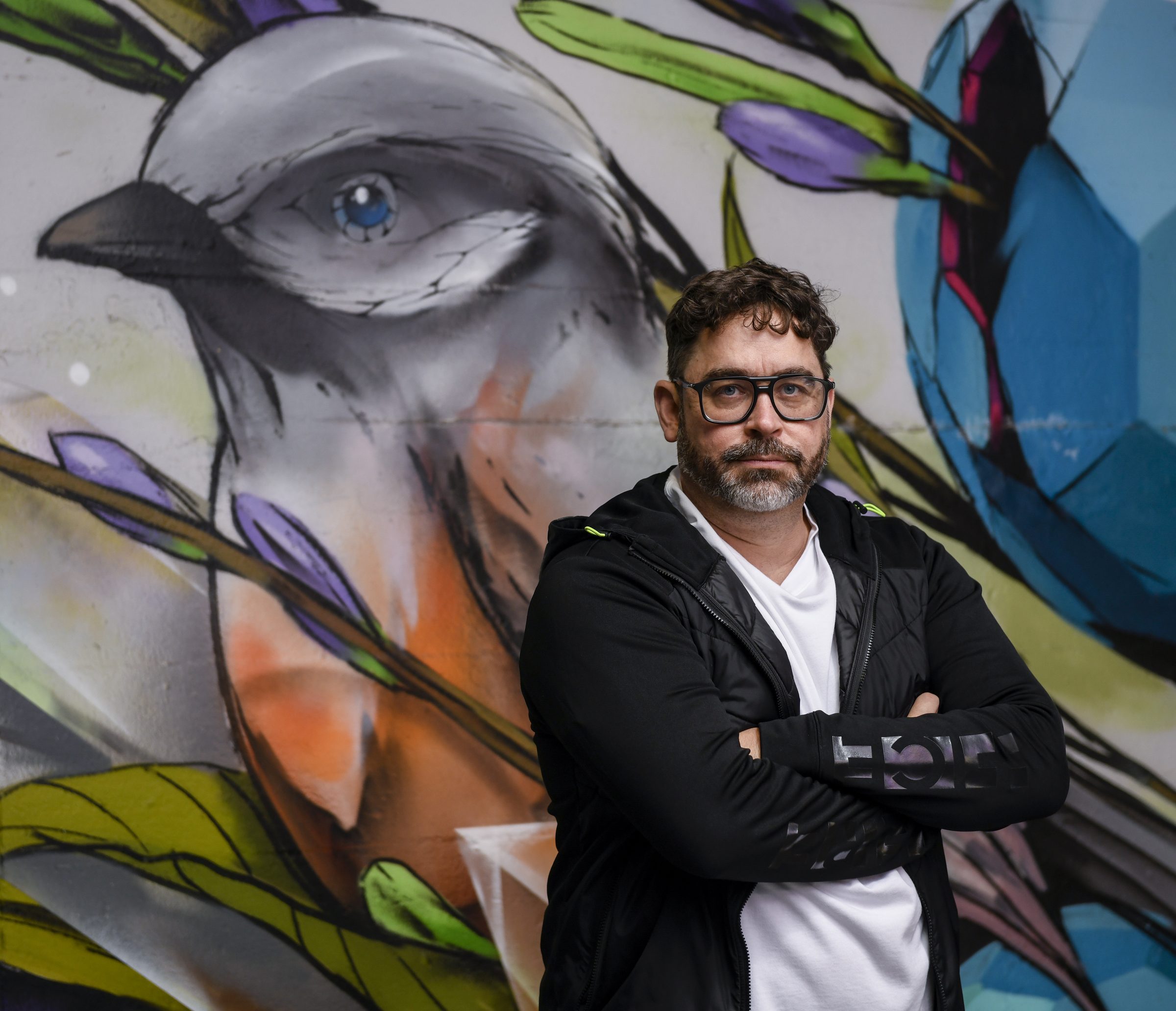 Andreas Zeisler mit verschränkten Armen vor einer bunten Street-Art-Wand